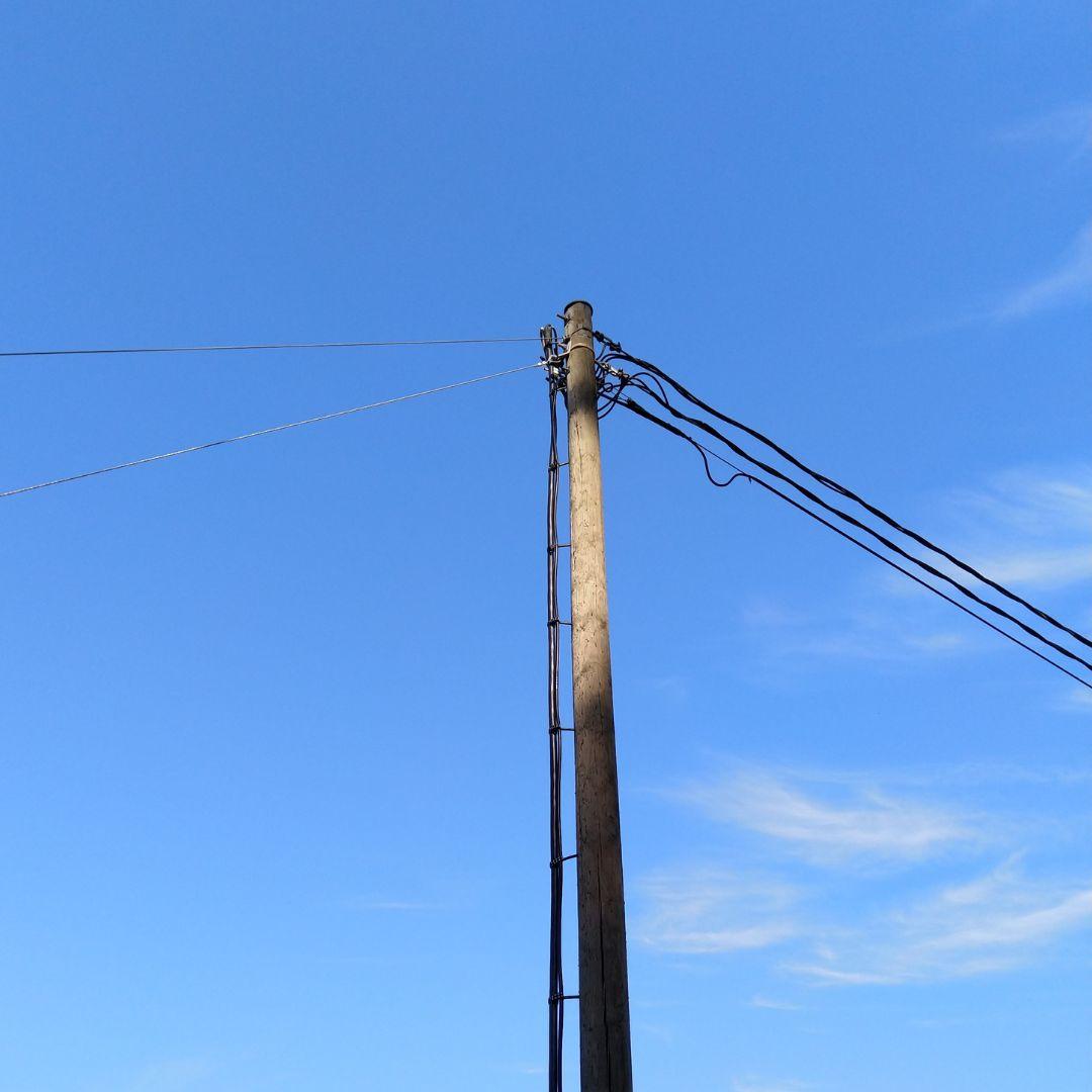 Pienjännitelinjan sähköylväs, jossa kulkee sähköjohdon lisäksi myös kaksi muuta johtoa.