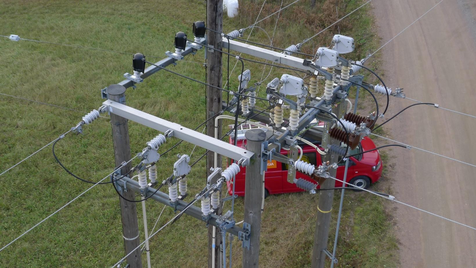 Sähkölinjojen risteyskohta, taustalla punainen KSS Energian auto.