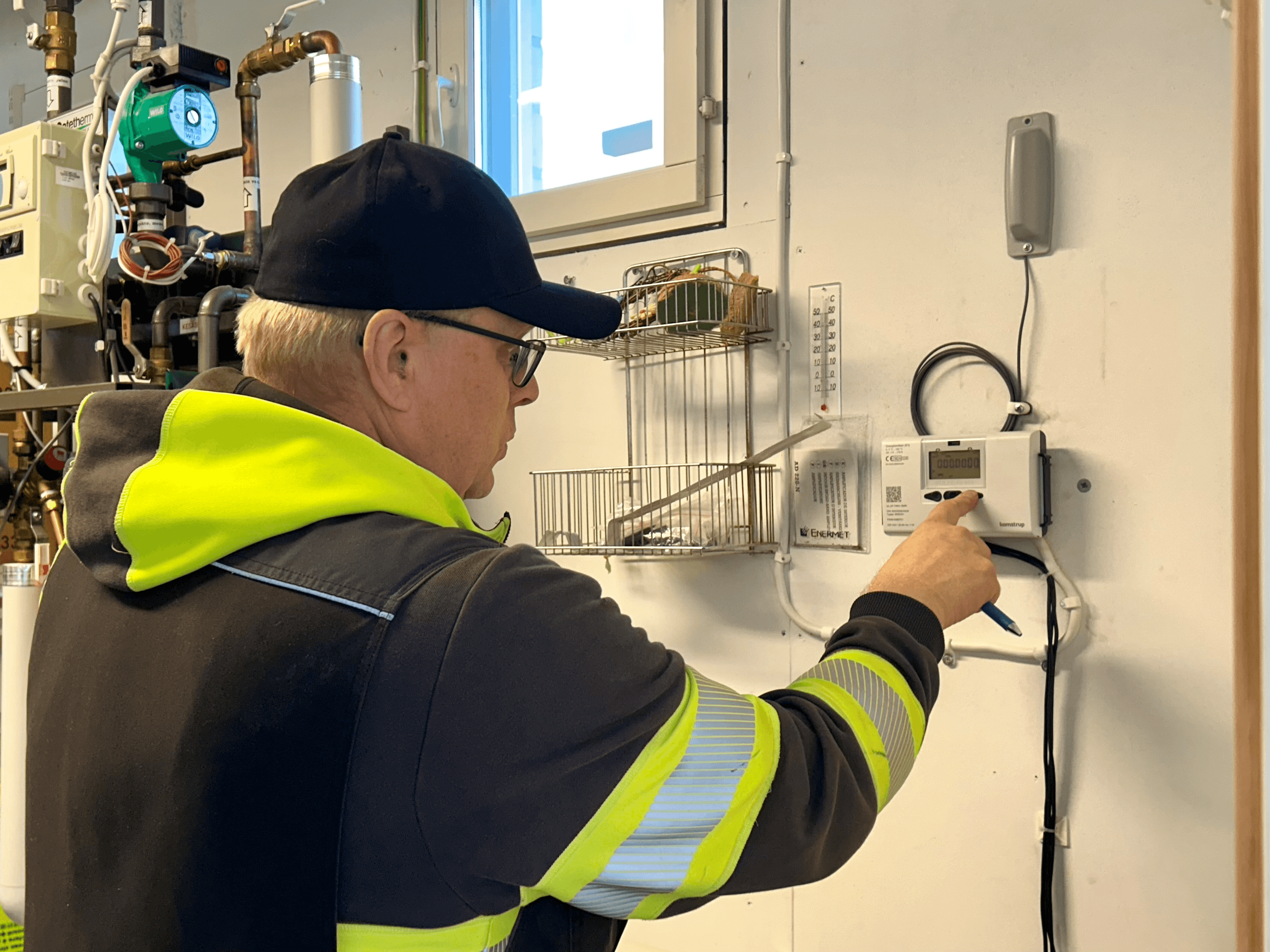Lämpöasentaja Janne Härkönen tarkastaa uuden kaukolämpömittarin toimivuuden.