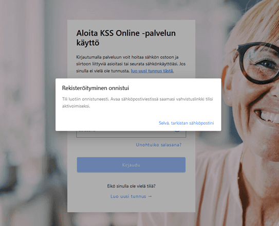 Kuvakaappaus sähköisen KSS Online -palvelun rekisteröitymisen onnistumisilmoituksesta. Edessä vaalealla pohjalla ilmoitus rekisteröitymisen onnistumisesta, taustalla näkyy pastellinvärisen taustakuvan sisältävä kirjautumissivu lomakkeineen. Taustakuvassa oikealla puolella vaaleahiuksinen ja leveästi hymyilevä silmälasipäinen nainen.